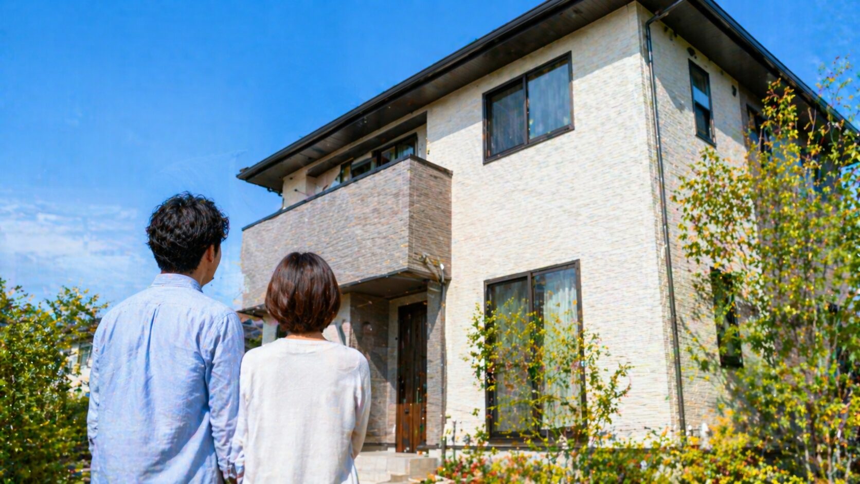外壁塗装が完了した美しい家を眺める夫婦